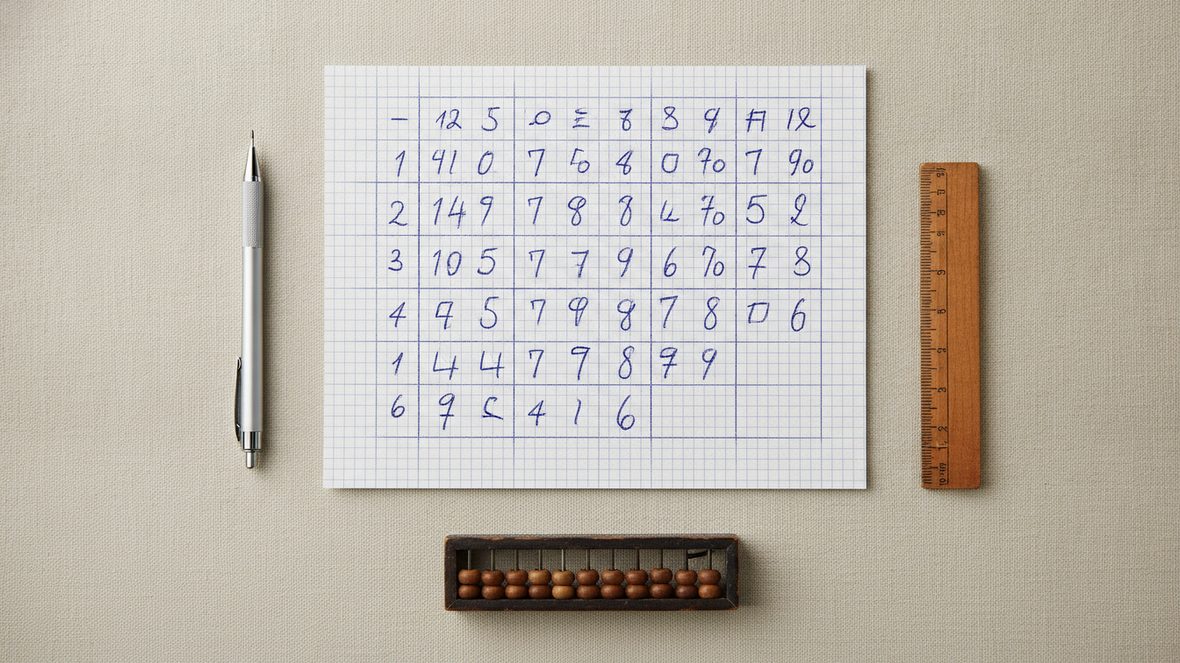 Feuille quadrillée couverte d'un tableau de nombres tracé à la main, crayon et règle de bois